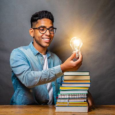 Student with stack of books holding lightbulb