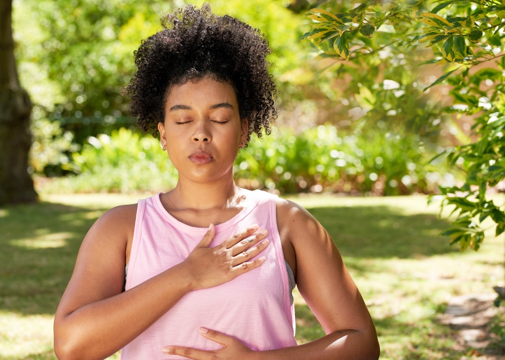 woman outside on sunny day with eyes closed focused on breathing