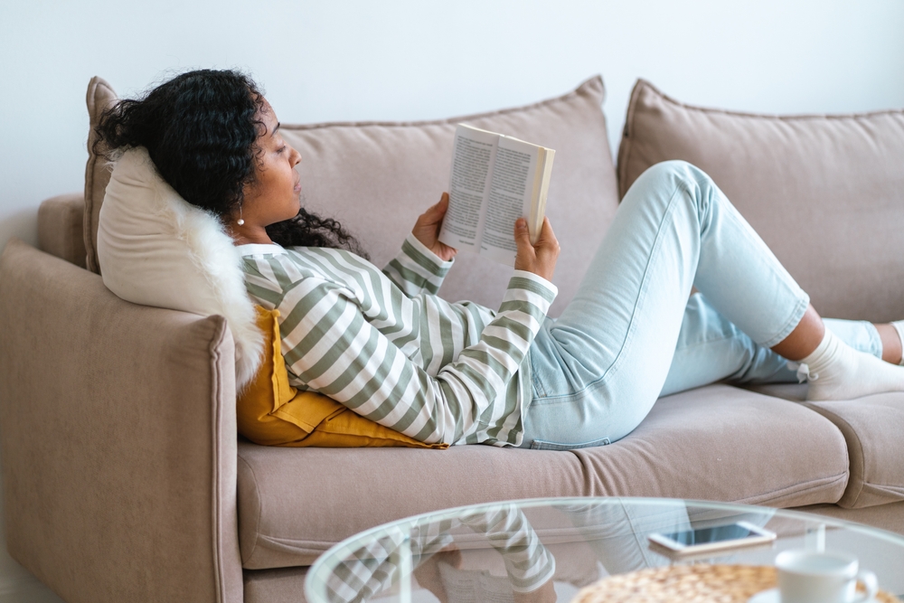 woman on couch reading book