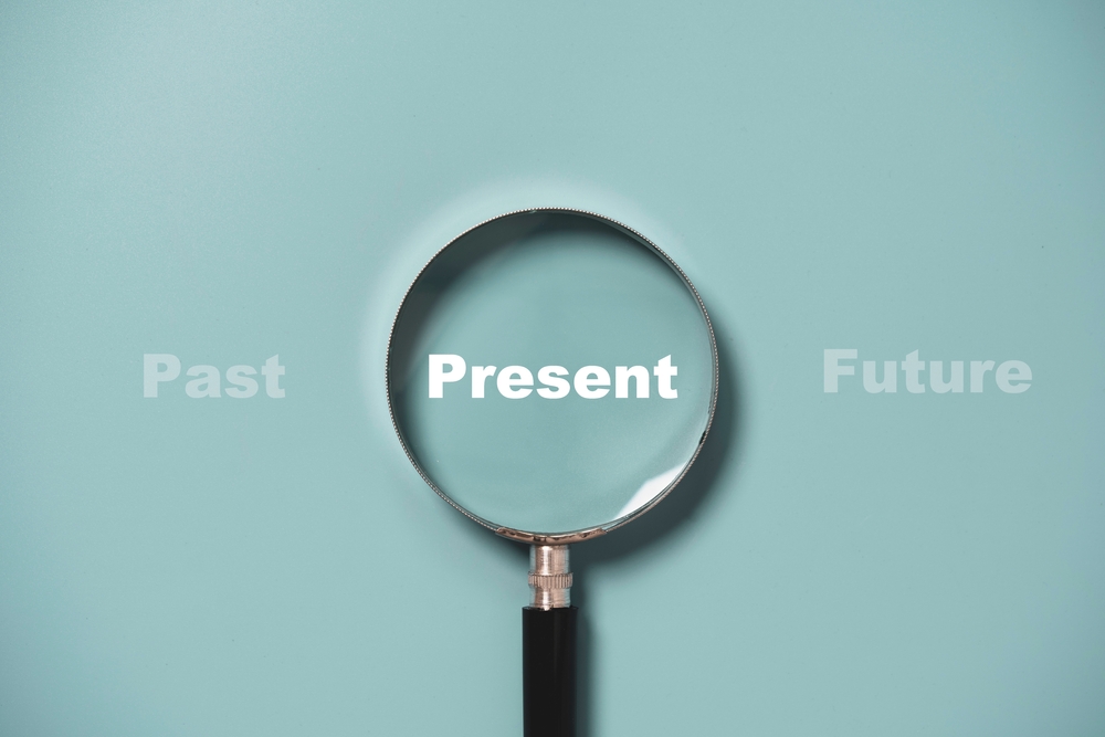 Words "Past" "Present" and "Future" with a magnifying glass over the word "Present"