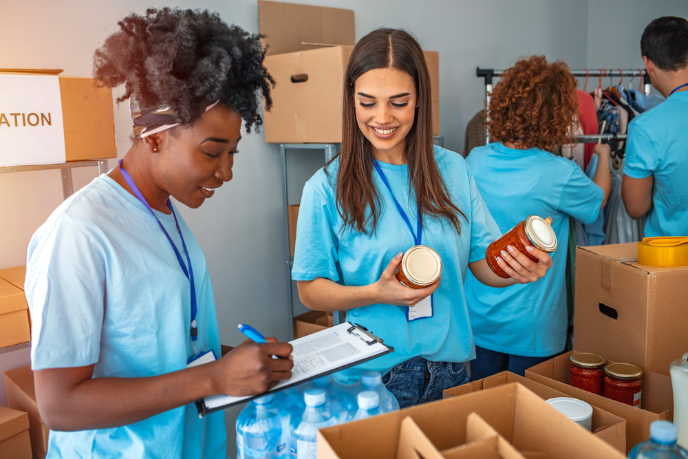 group of student voulenteers with blue shirts organizing cans for food drive