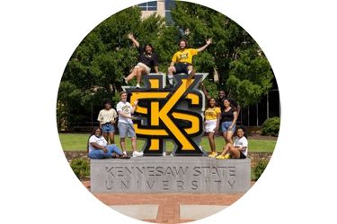 Students sitting on the main KS logo on the Kennesaw Campus