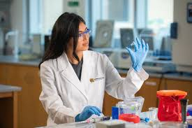 Student in Kennesaw State Labcoat looking at small container