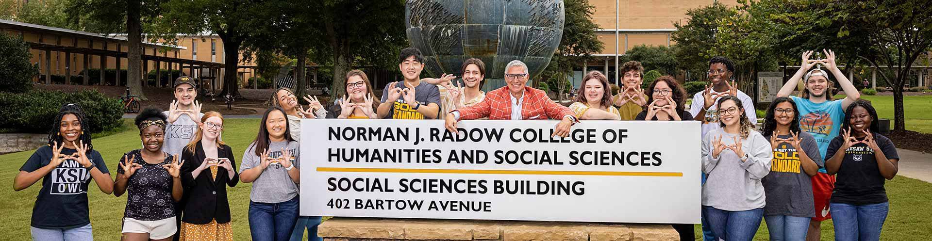 Norman J. Radow with Students around college sign