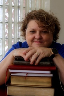 Lisa M. Russell leaning against her books