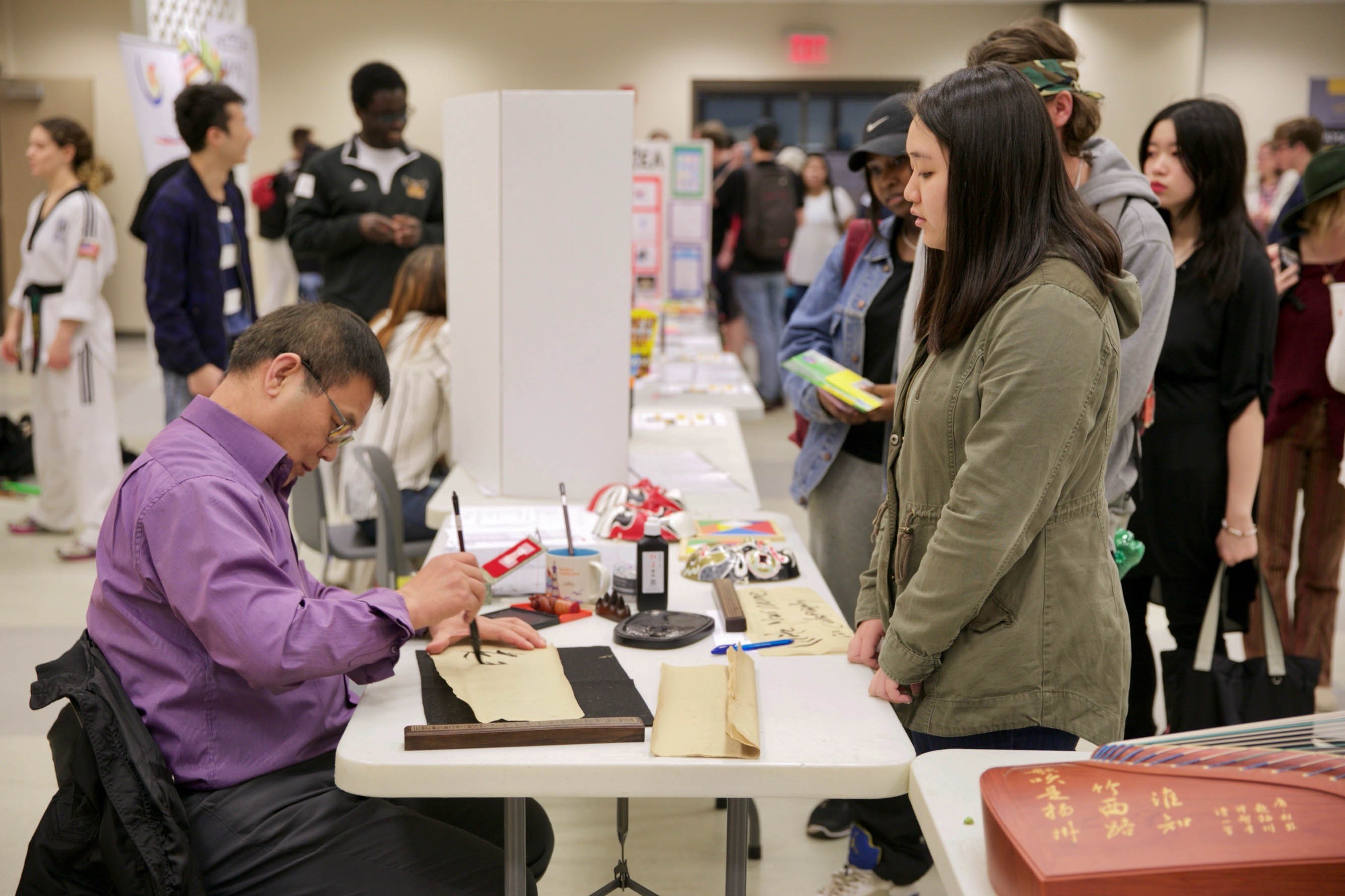  A student watches one of the demonstrators practice Chinese calligraphy during Foreign Language Day on March 21. Photo credit: Felix Amaya