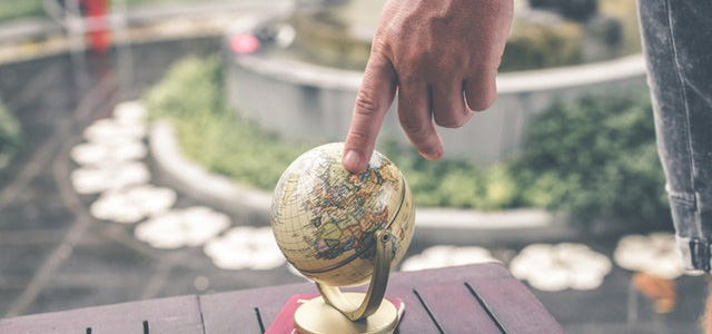 A finger pointing to a spot on a small globe